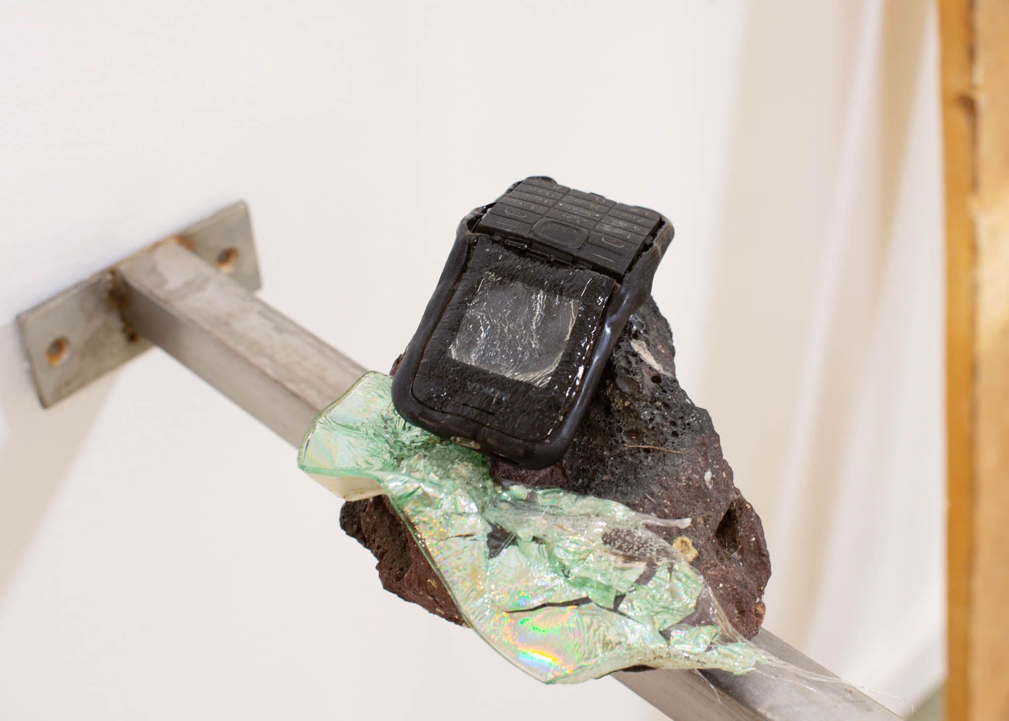 A melted phone and bits of plastic lay over a stone