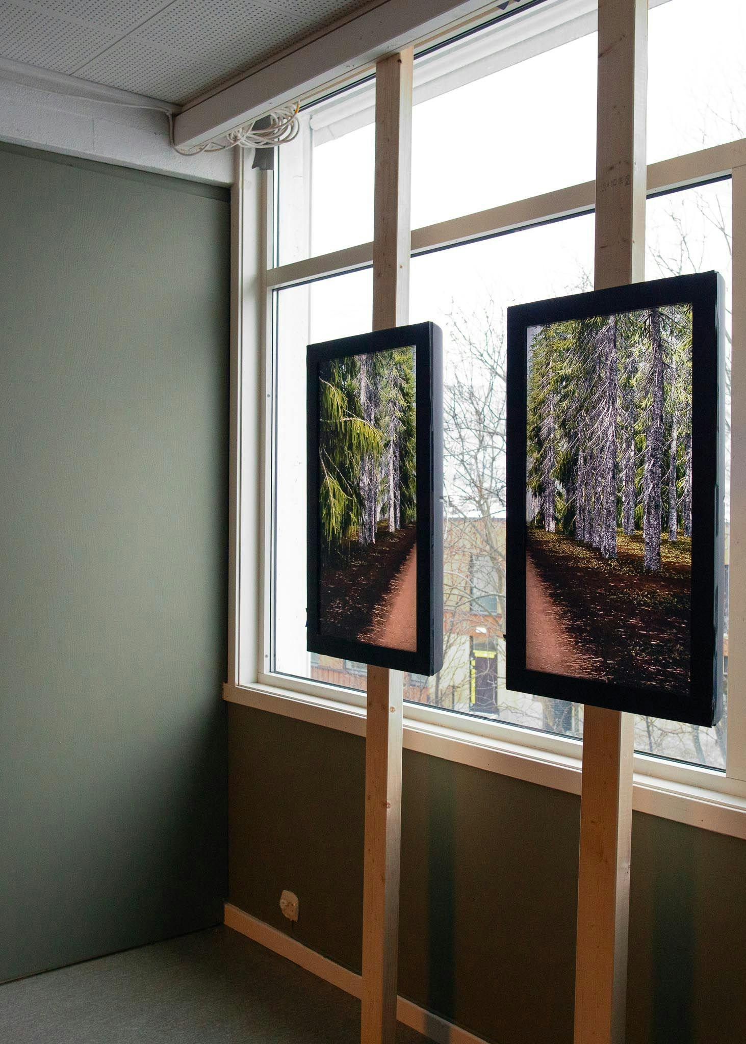 Two screens mounted vertically in front of a window, each showing one half of the film.
