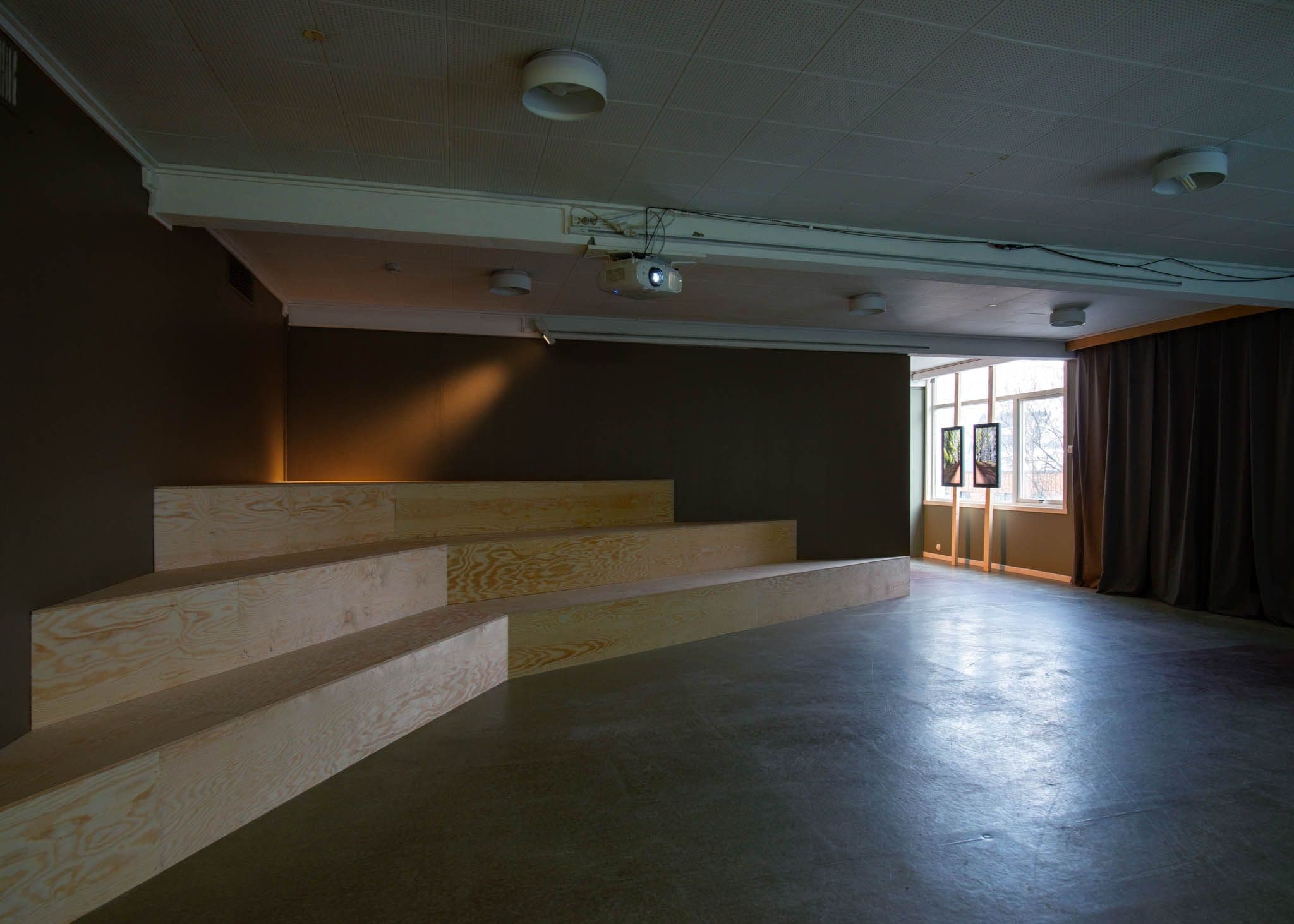 A wooden amphither with three tiers is lit with a spotlight.