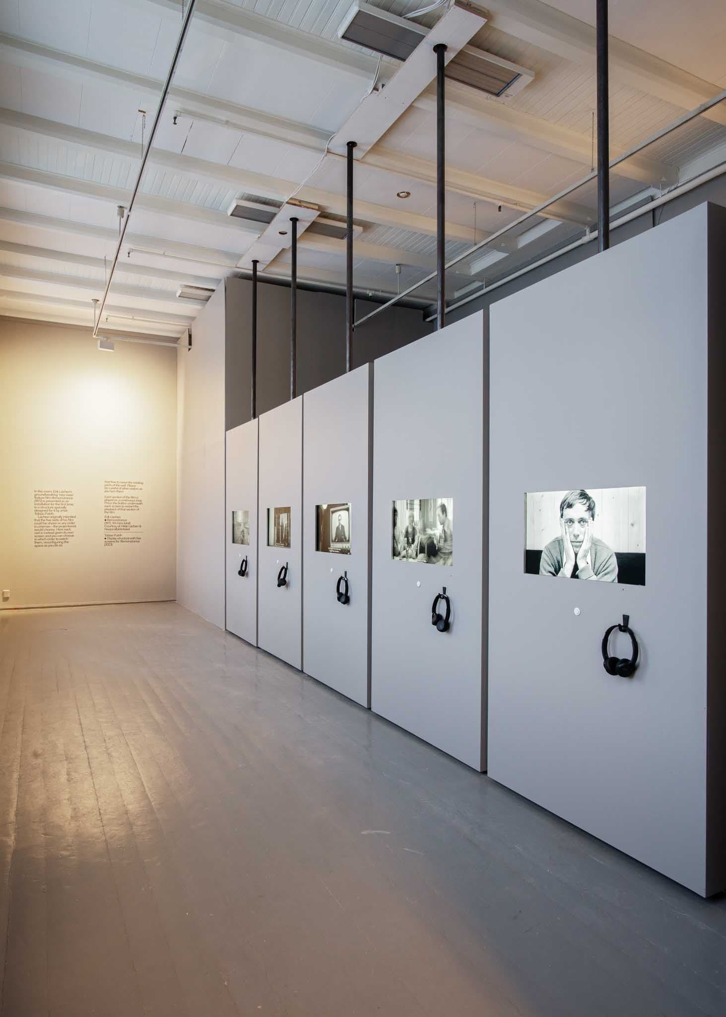 Vertical panels are aligned in a wall, with TV screens in each showing a black and white image.