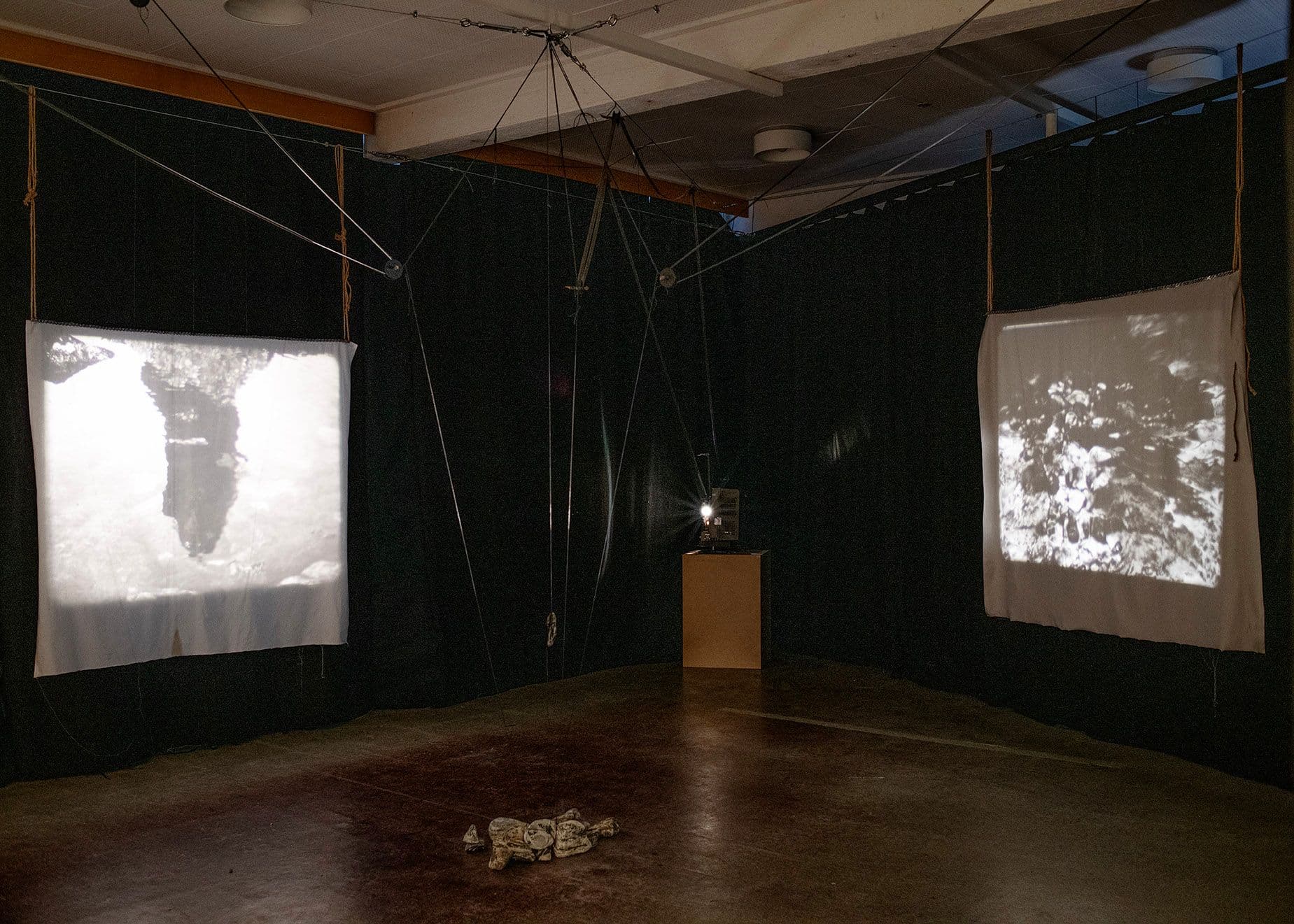 En analog projektor mellom to lerret i et mørkt rom